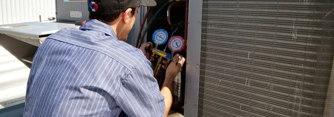 HVAC technician servicing a condenser unit in Harrisburg